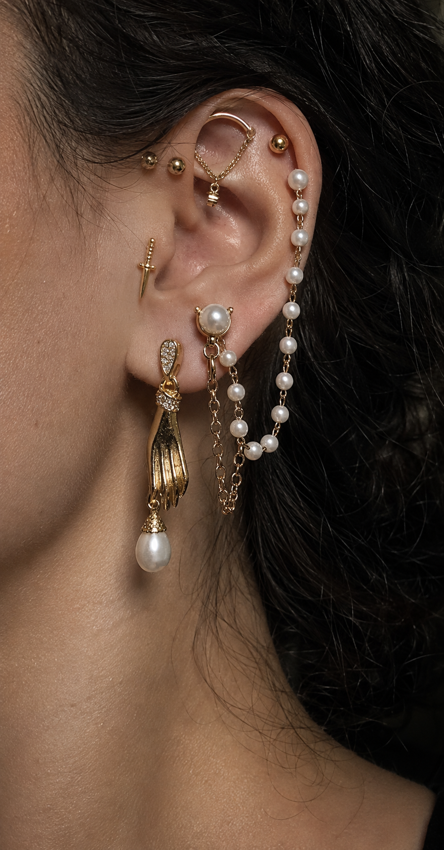 Composition de piercings d’oreille avec bijoux dorés, chaînes, perles et dague chez HOBOH à Aix-en-Provence